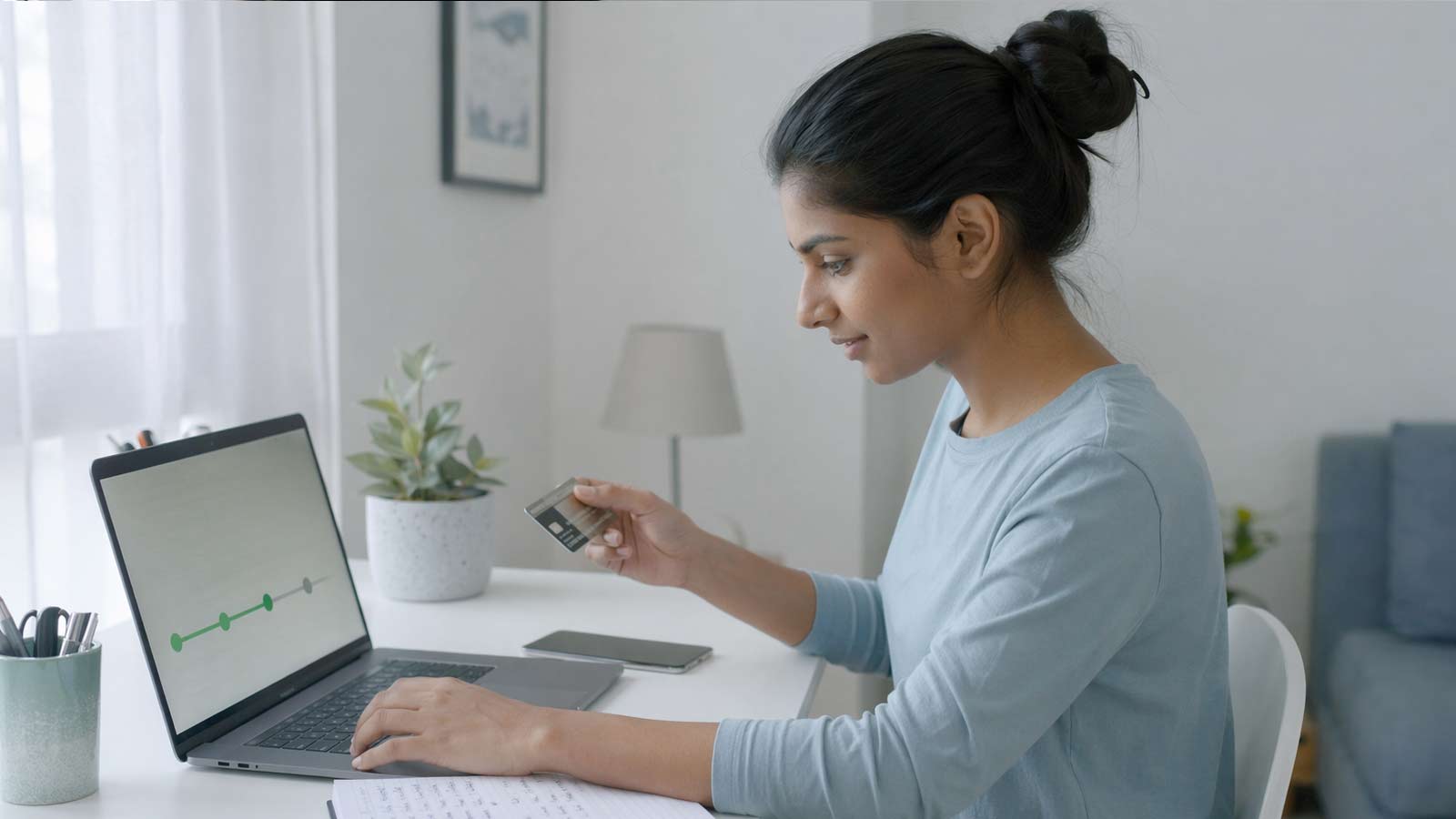 person reviewing credit building timeline on laptop with credit card at home desk