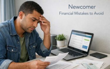 Newcomer reviewing financial documents and cards at home desk avoiding money mistakes